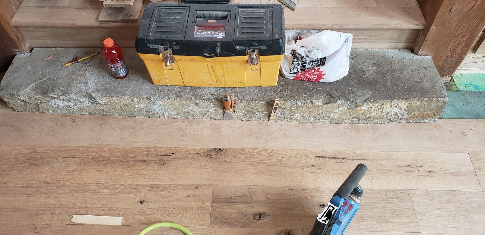 Oak hardwood installation in progress around stone hearth